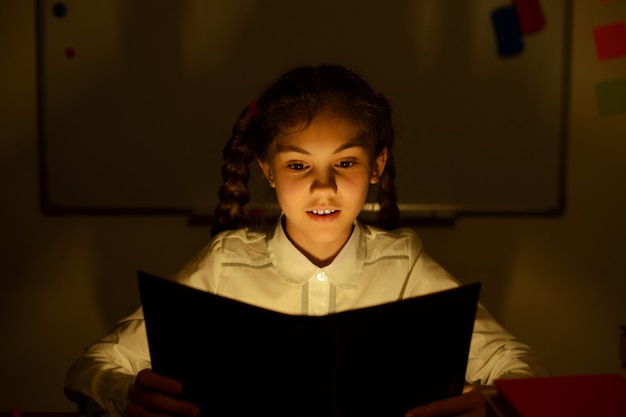 Photo small girl reading a book in the classroom