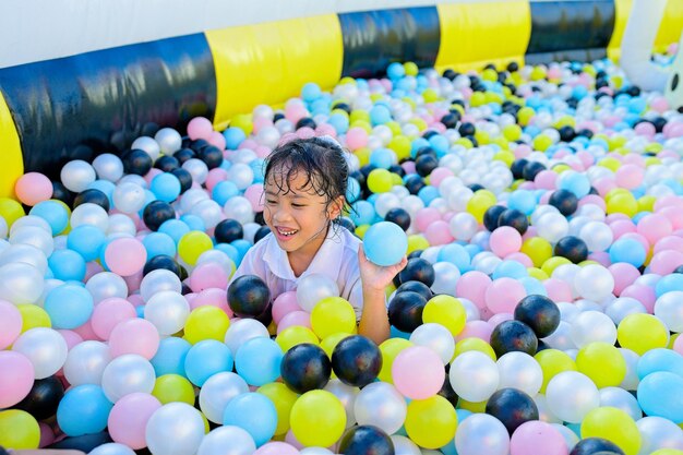 Small girl in school uniform playing in bouncing ball house on summer holiday