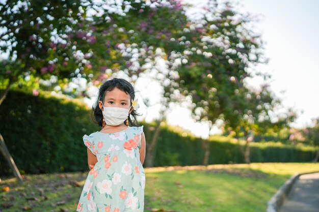 Small girl standing at field with protective face mask