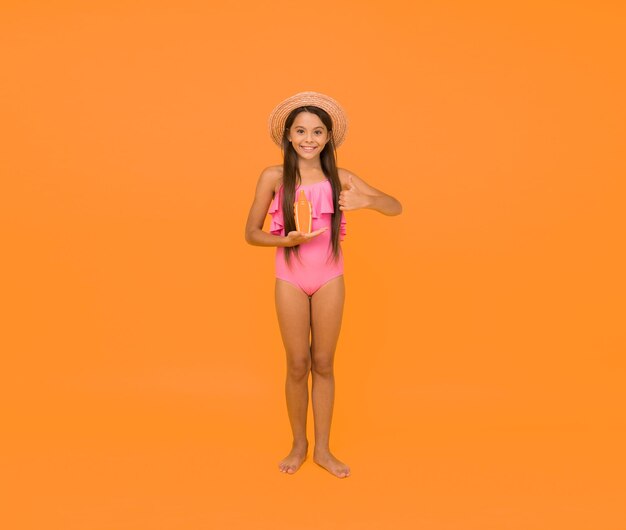 Small girl in swimsuit hold sunscreen cosmetics cream spf lotion concept