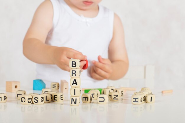 Small girl of two years composes words from letters. Closeup