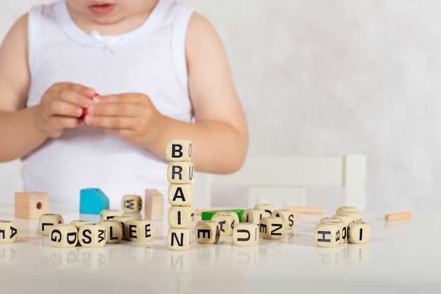 Small girl of two years composes words from letters. Closeup