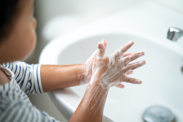 Small girl washing hands in sink Personal hygiene concept