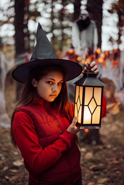 Маленькая девочка с фонарем в лесу с призраком на заднем плане