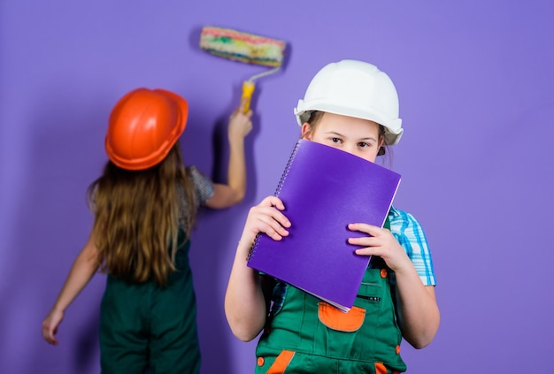 Small girls repairing together in workshop foreman inspector\
repair labor day 1 may engineering idea future career little kids\
in helmet with tablet and roller what seems to be a problem