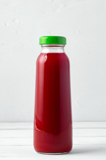 Small glass bottle of fresh juice on white background