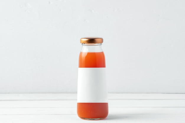 Small glass bottle of fresh juice on white background