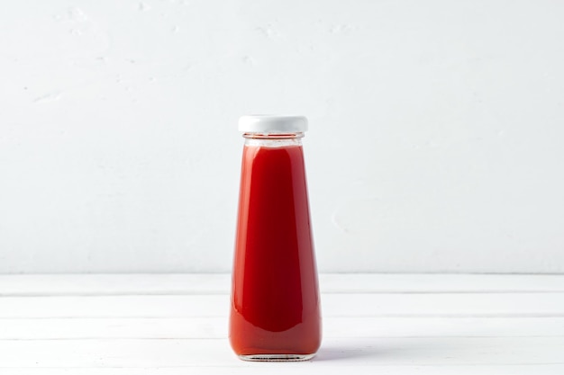 Small glass bottle of fresh juice on white background