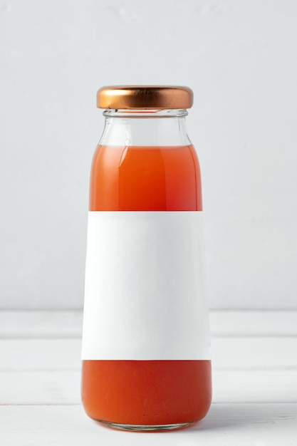 Small glass bottle of fresh juice on white background