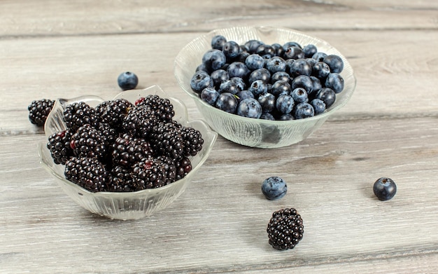 Small glass bowl of blueberries and blackberries on gray wood desk