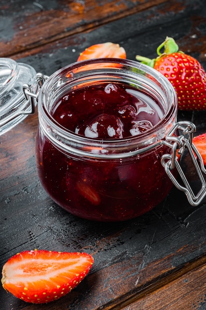 Small glass bowl, of red berry jam, on old dark  wooden table background