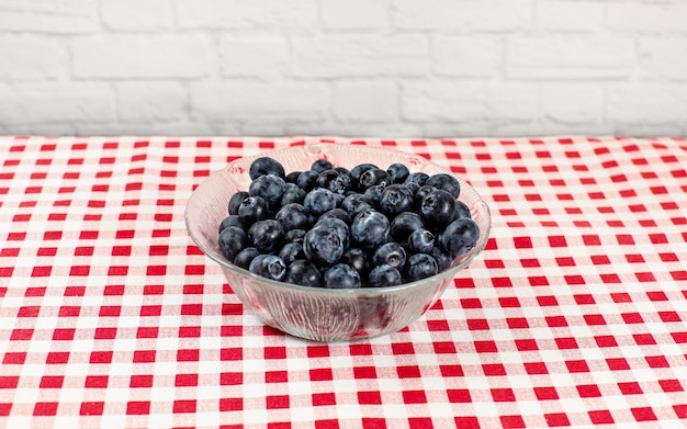 Small glass bowl with blueberries on red gingham patter tablecloth