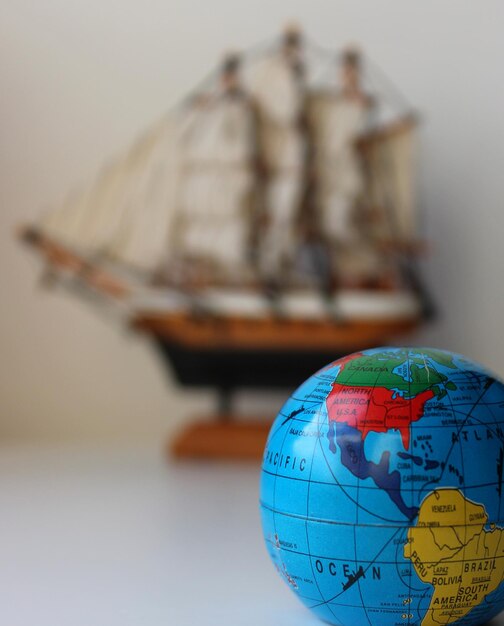 Small Globe With Mapped Travel Routes And Defocused Masted Ship Toy On Background