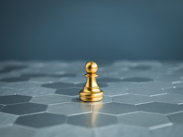 The small golden pawn chess piece standing alone on hexagon pattern chessboard on blue background Leader influencer lonely commander strong and business strategy concept