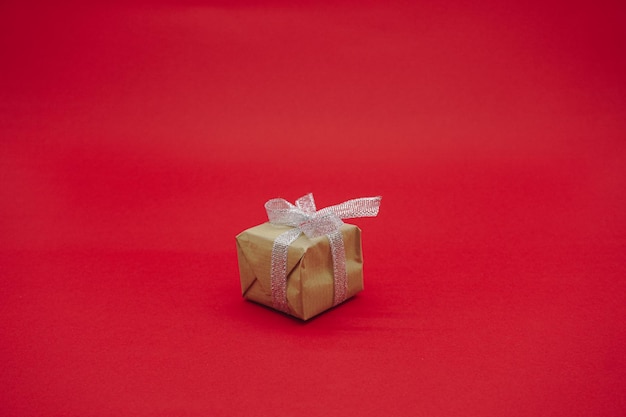 Small green gift box with gray ribbon. christmas gift box.\
isolated on a red background