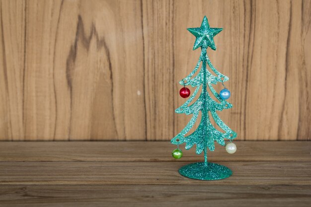 木製のテーブル上に小さな緑の金属のクリスマスツリー