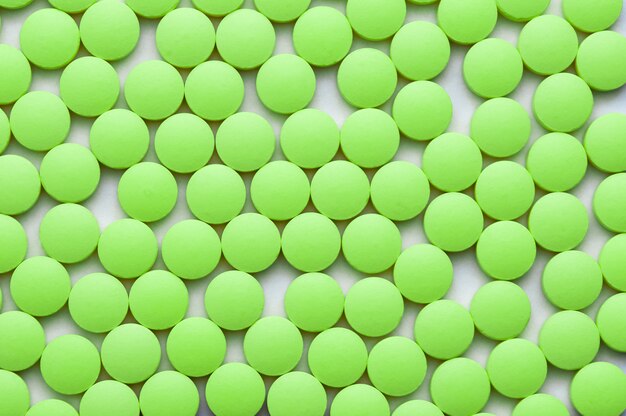 Small green pills on a white background close-up.