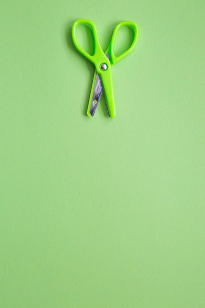 Small green scissors on pistachio green background