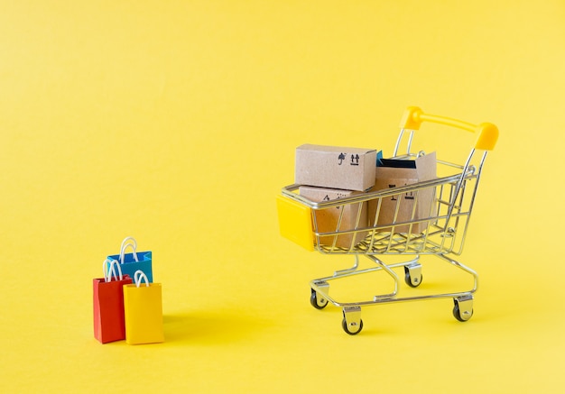 A small grocery cart with boxes and bags on a yellow background