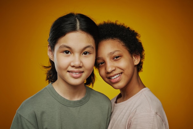 Small group of cute intercultural preteen girls in tshirts standing close to each other and looking