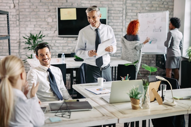 Small group of smiling business people having a meeting in the office and communicating Focus is on mid adult businessman