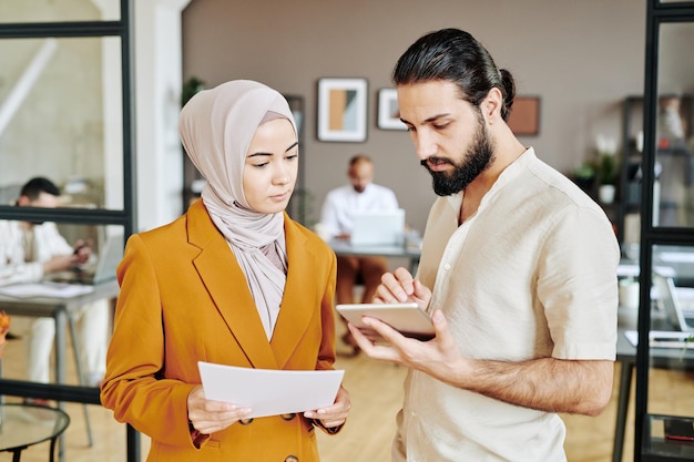 Small group of young muslim white collar workers discussing online information