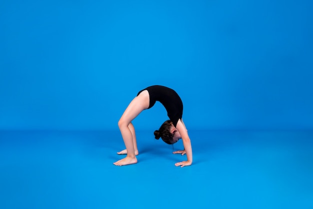 A small gymnast performs a bridge exercise on a blue background with a place for text