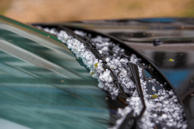 激しい夏の嵐の後、黒い車のフードに小さな雹の氷のボール