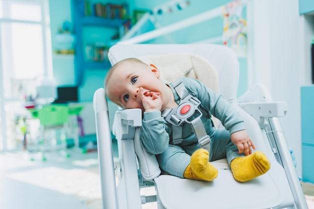 A small handsome boy is sitting in a high chair for feeding Children's kitchen chair for eating Children's furniture