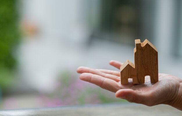 Small home model on hand with bokeh background, miniature house