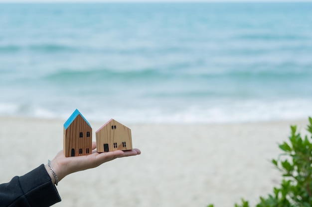 Small home model on hand with sea background miniature\
house