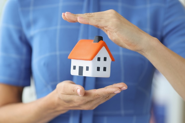 Small house in female hands of air home insurance concept