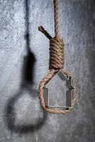 Photo small house framed with hangman's noose over the grey concrete wall