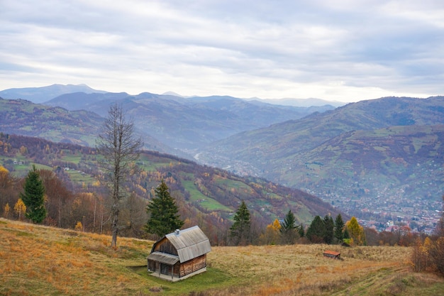 a small house sits in a field with mountains in the background