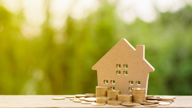 Small house and a stack of golden coins in the garden