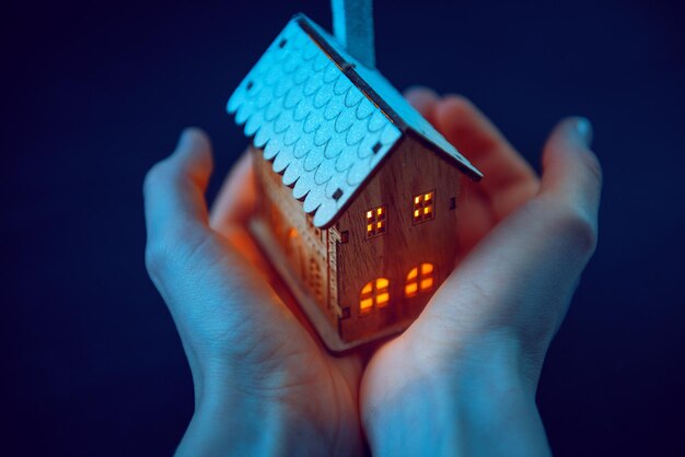 Small house with luminous windows in female hands