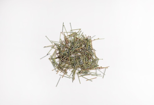 Small iron nails lie in a heap on a white background. Wholesale purchase of nails