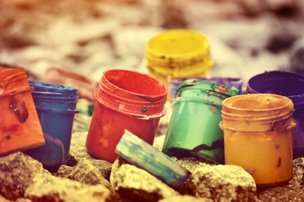 Small jars from under paint of different colors on gray pebbles