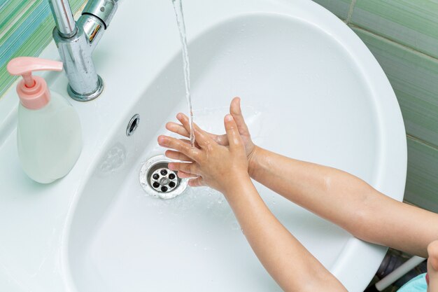 Small kid, child washes his hands under the tap in the sink