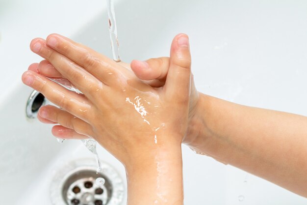 Small kid, child washes his hands under the tap in the sink