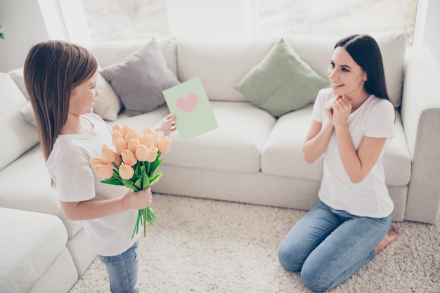Small kid daughter give mommy roses bouquet postcard  in house indoors