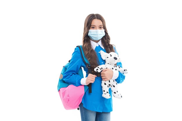 Small kid in protective medical mask back to school with toy dog during COVID-19 pandemic, education.