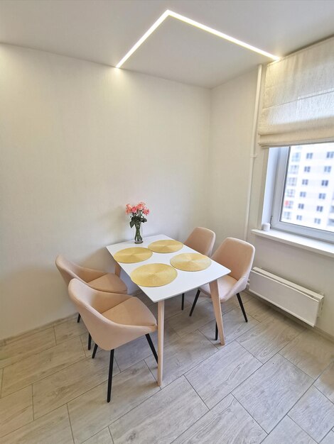 Small kitchen corner with white walls a dining table and beige armchairs Vase