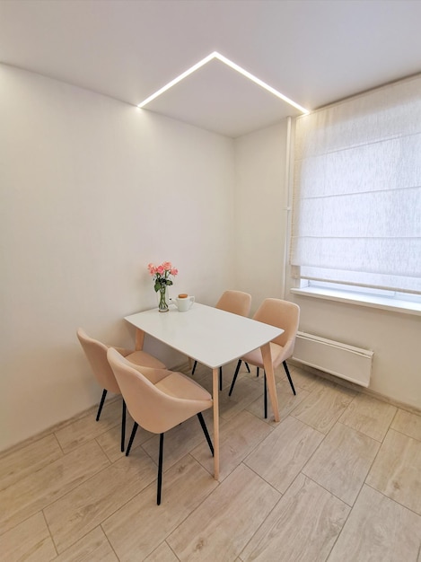 Небольшой кухонный уголок с белыми стенами, обеденный стол и бежевые кресла.