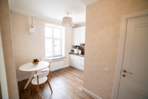 A small kitchen with a table and chairs in a room with a window and a lamp.