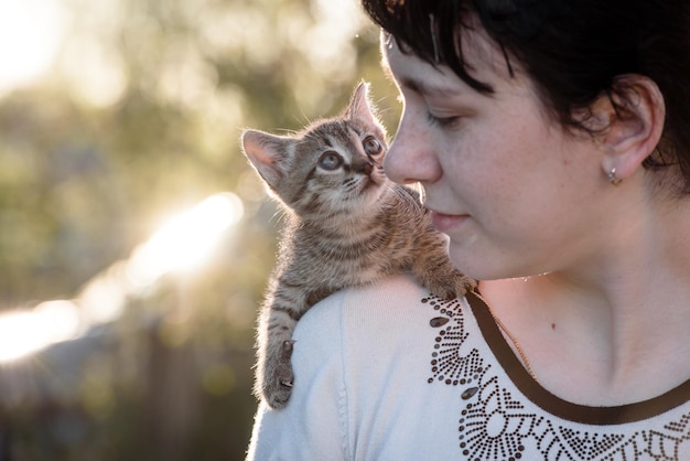 A small kitten sitting on the shoulder of a girl on a walk