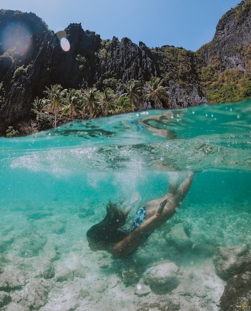 Фото Небольшая лагуна в эль нидо. женщина, наслаждаясь время в кристально прозрачной воде, с тропическими джунглями. понятие о путешествии и природе
