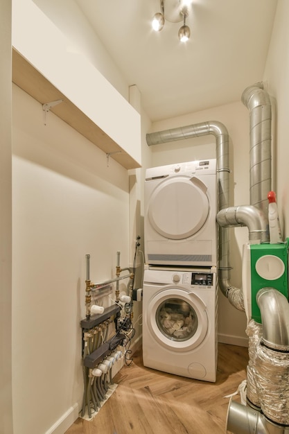 A small laundry room with a washing machine and dryer as well\
as pipes