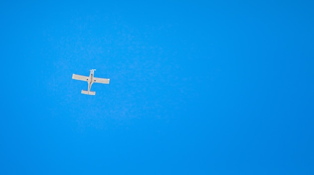 A small light plane flies in the clear sky. view from below.\
horizontal orientation.