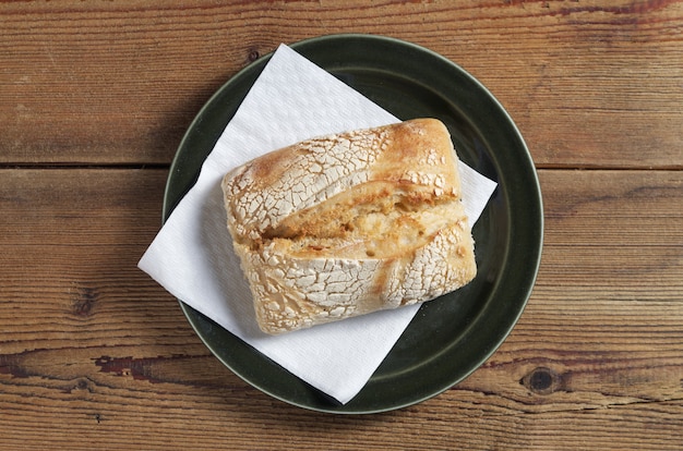 Small loaf of bread on a plate on wooden table